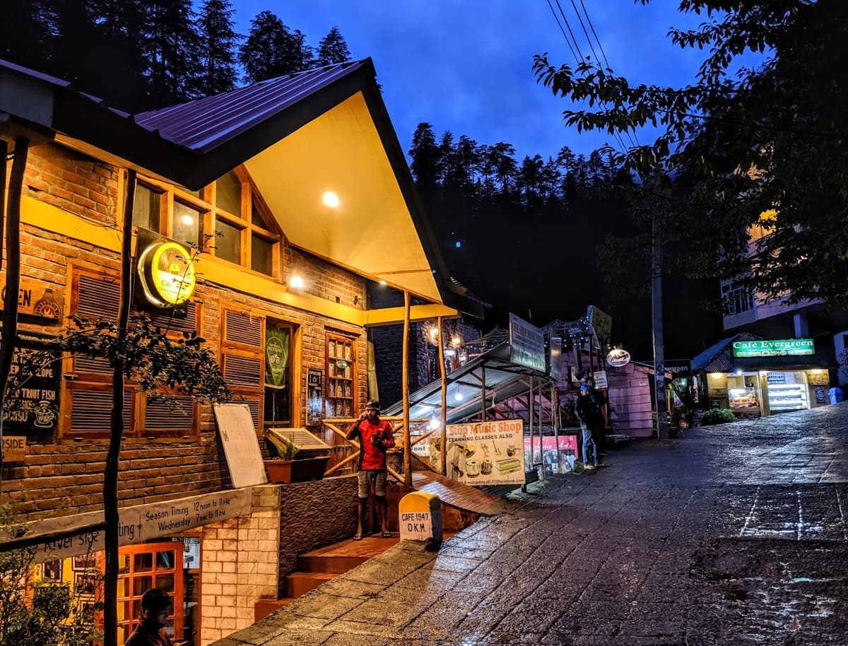Wooden cafes and shops lining a street in Old Manali at dusk