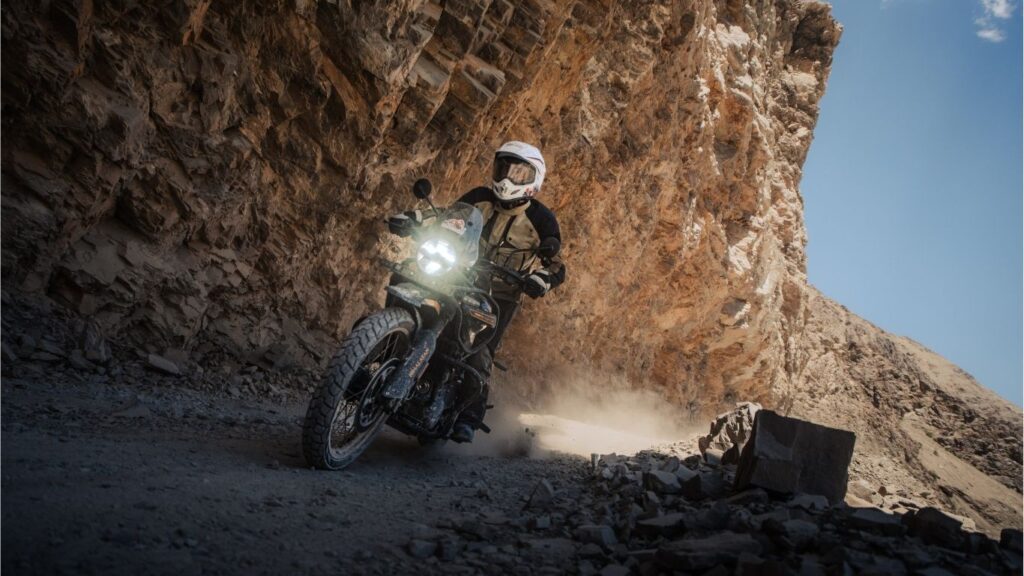 Motorcyclist riding adventure bike on rent rocky mountain road during winter in Himachal Pradesh.