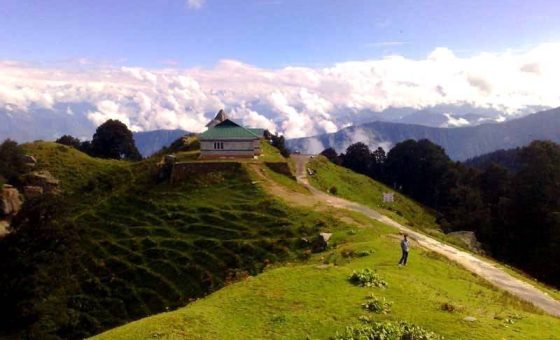 Serolsar Lake in Jibhi, Himachal Pradesh, surrounded by lush green mountains and cedar forests.